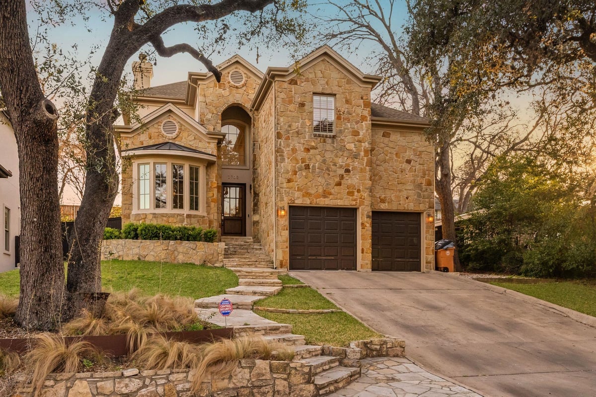 View 2703 McCullough ST in Thomas Place 2703 McCullough ST - front exterior with stone facade and mature oak trees - Luxury home in Thomas Place, Austin, TX