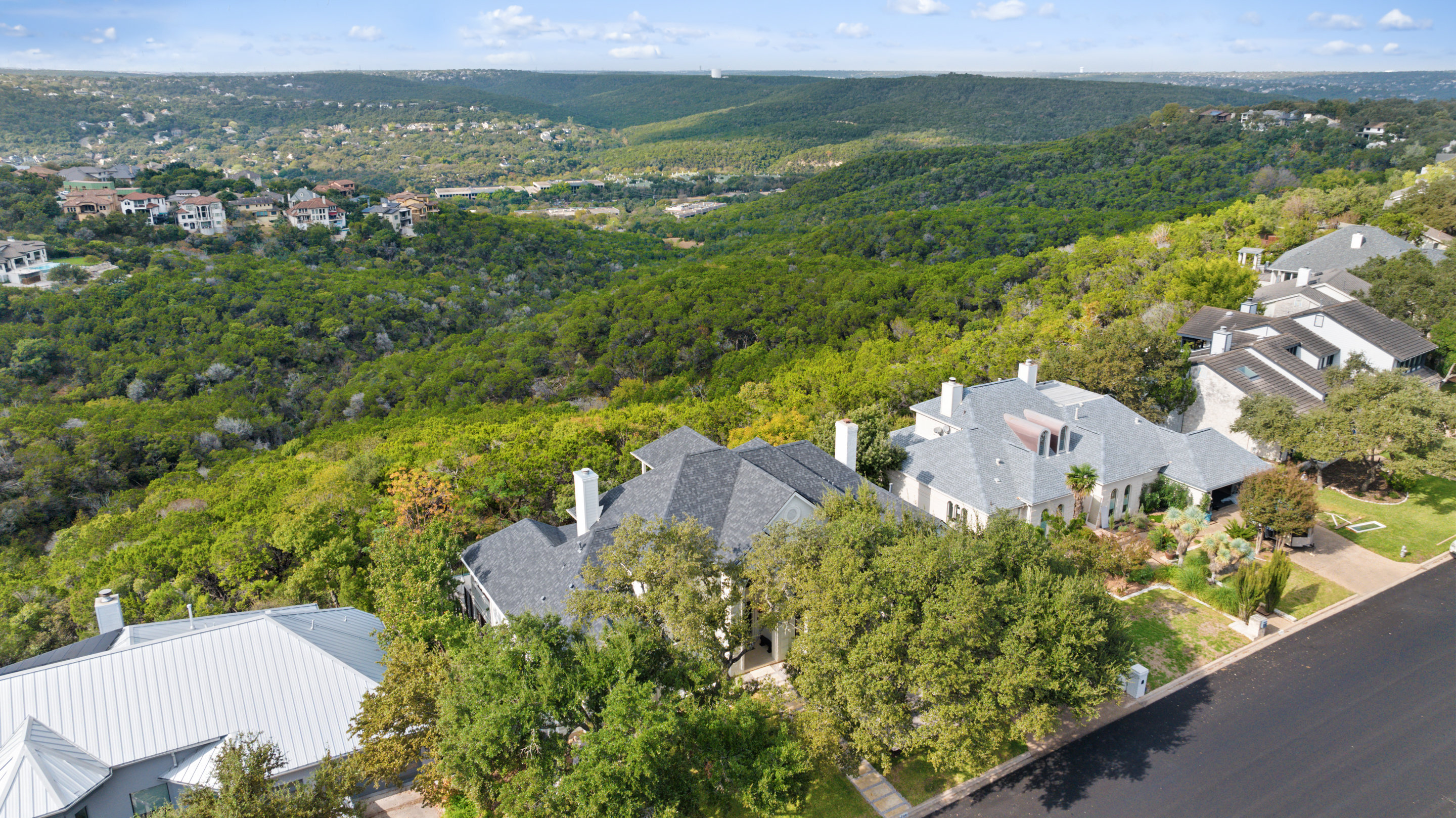 Aerial view of Northwest Hills homes and Hill Country terrain at golden hour
