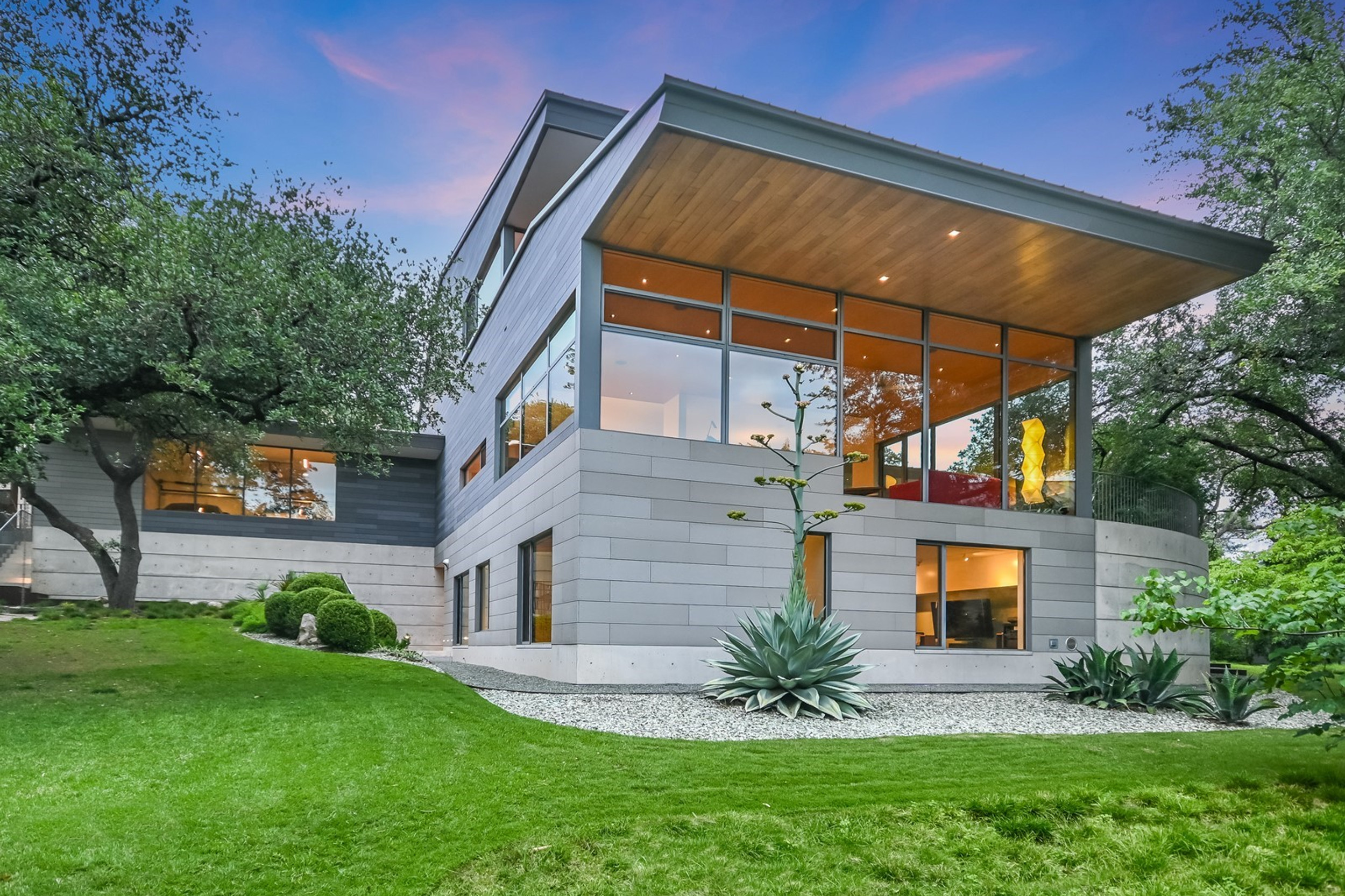 Wide view showing the three-story composition among mature trees
