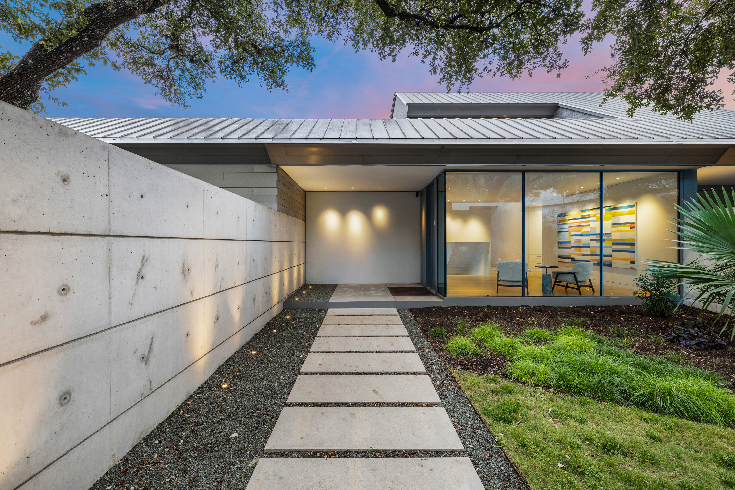 Front entry with form board concrete walls and stepping stone path at twilight