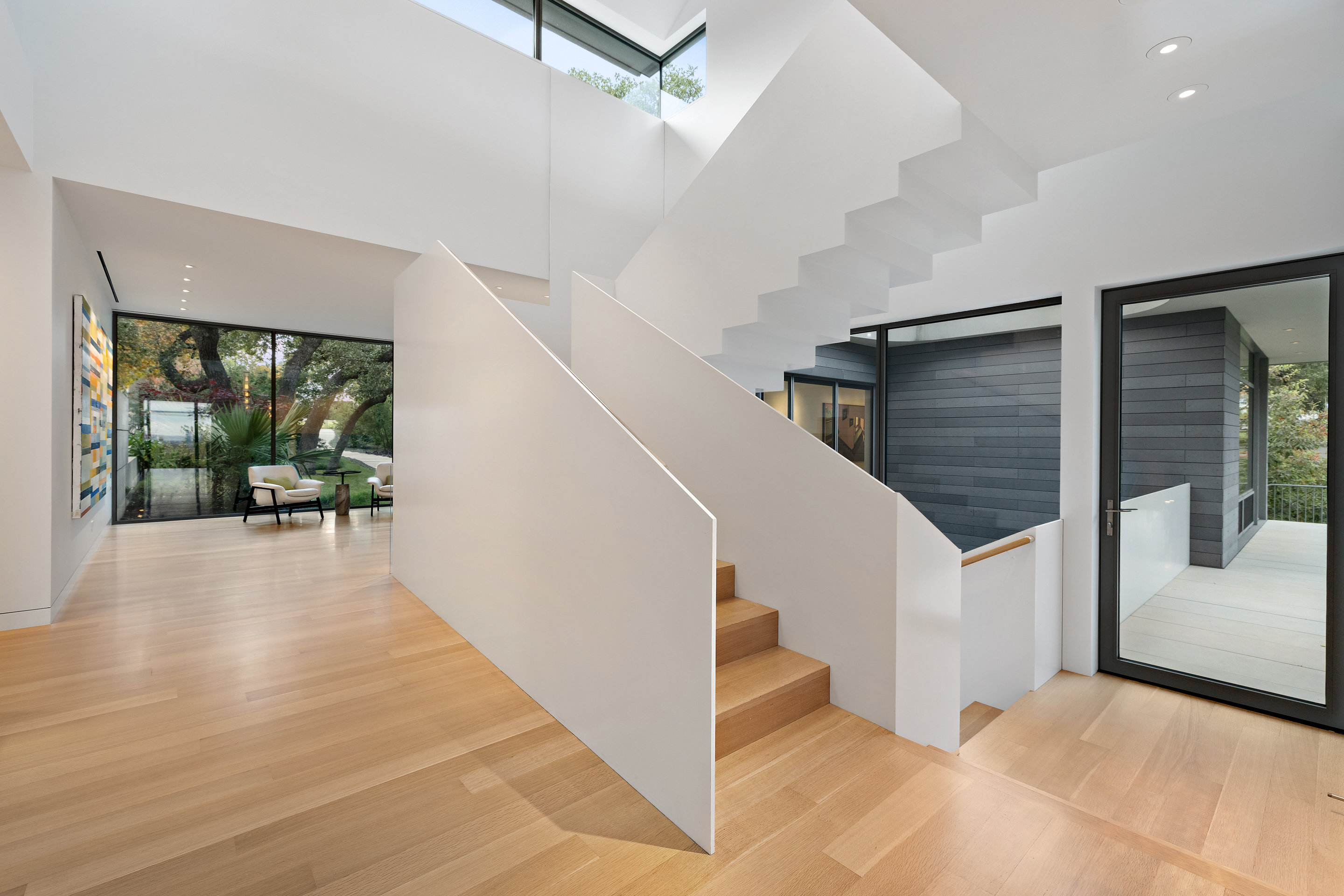 Three-story sculptural staircase with white oak treads and clerestory skylight
