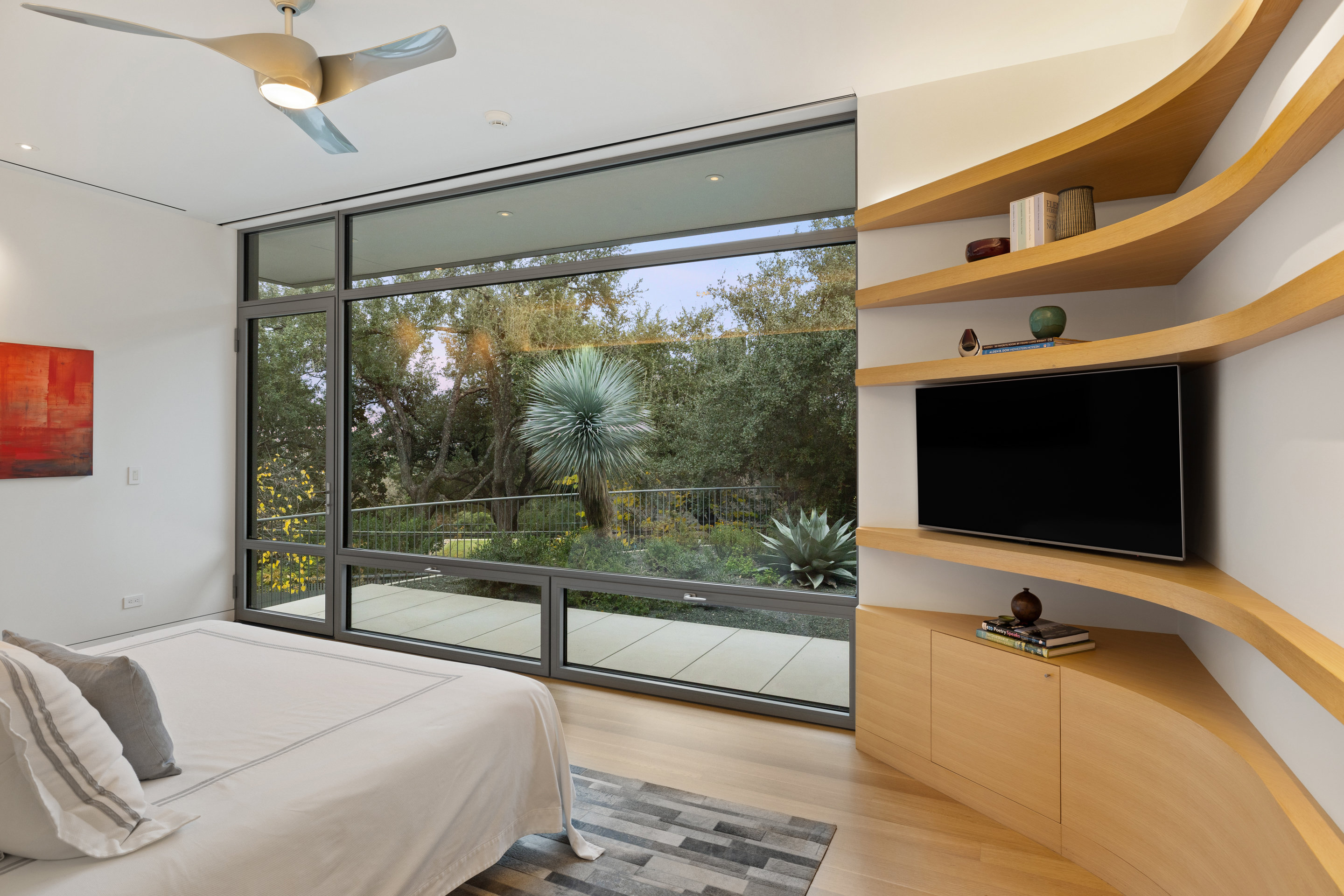 Guest bedroom with sculptural wave shelving and floor-to-ceiling garden view