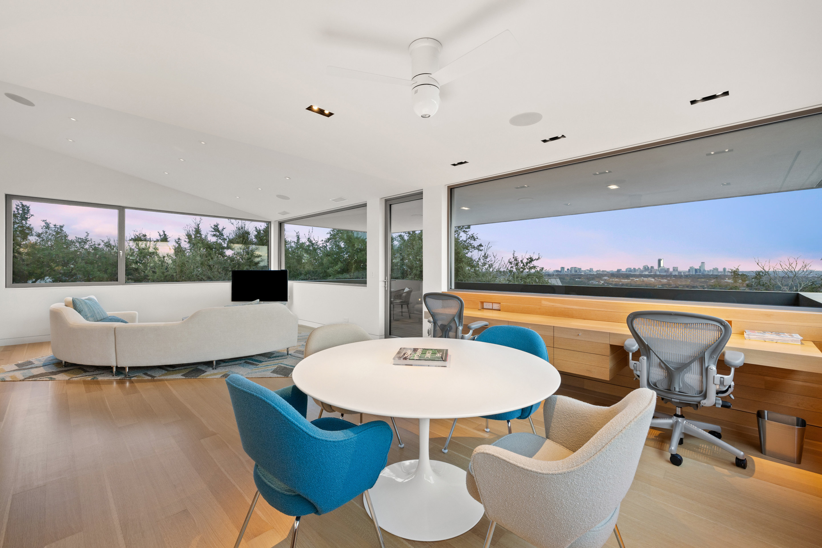 Upper-level office and lounge with panoramic downtown and Hill Country views at twilight