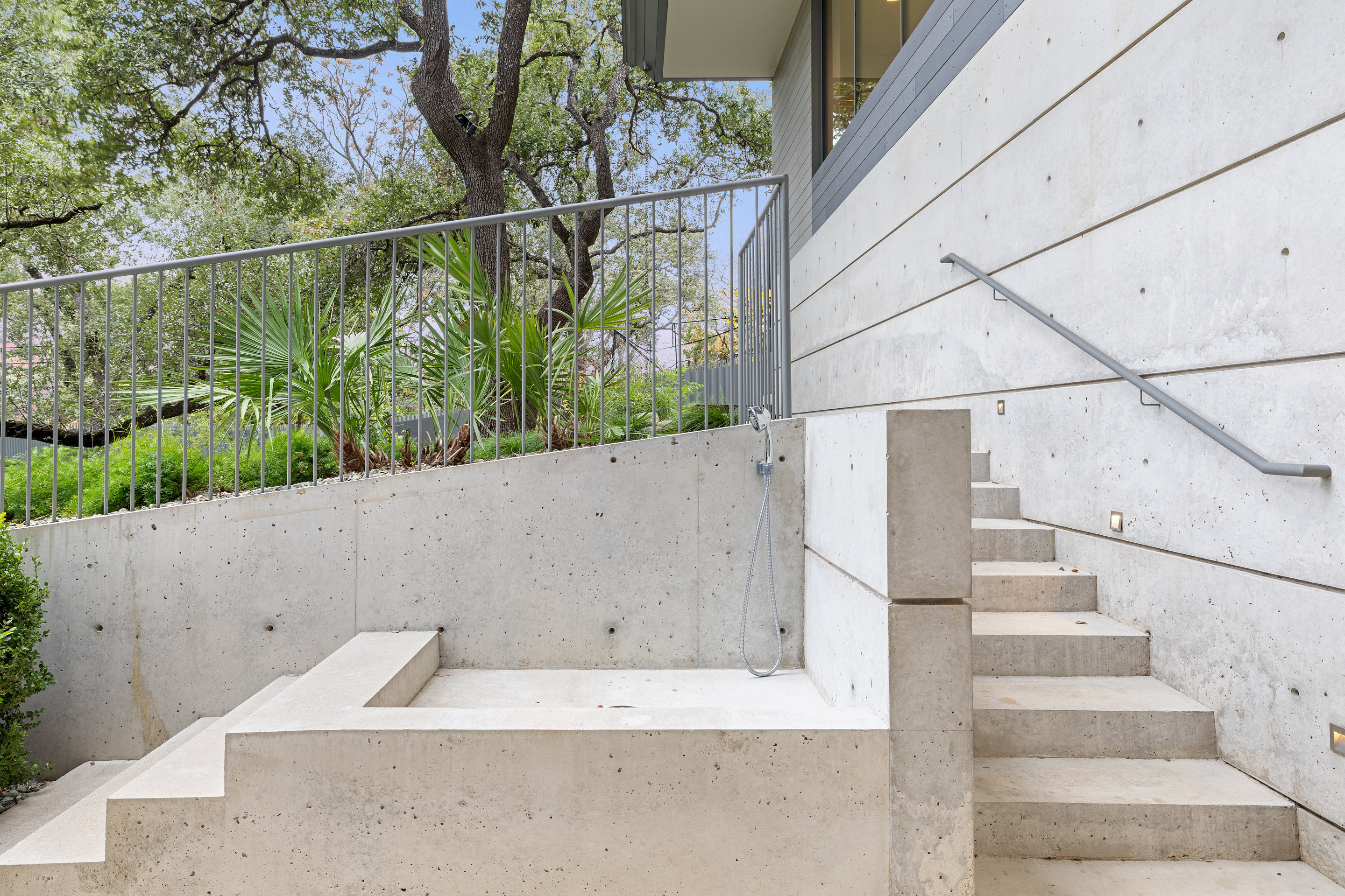 Outdoor concrete shower and steps beneath live oak canopy