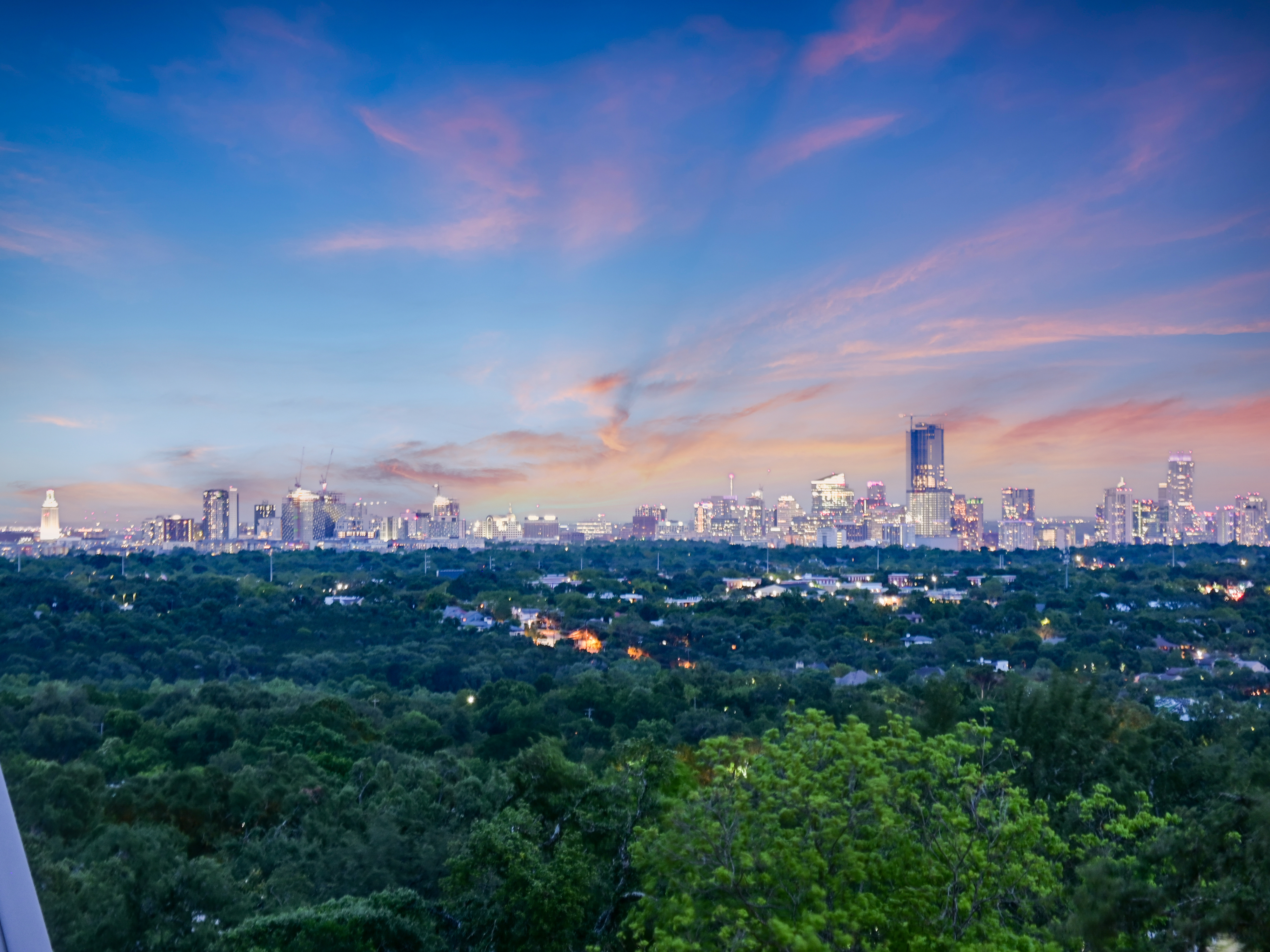 Sweeping tree-top view toward downtown Austin at golden hour