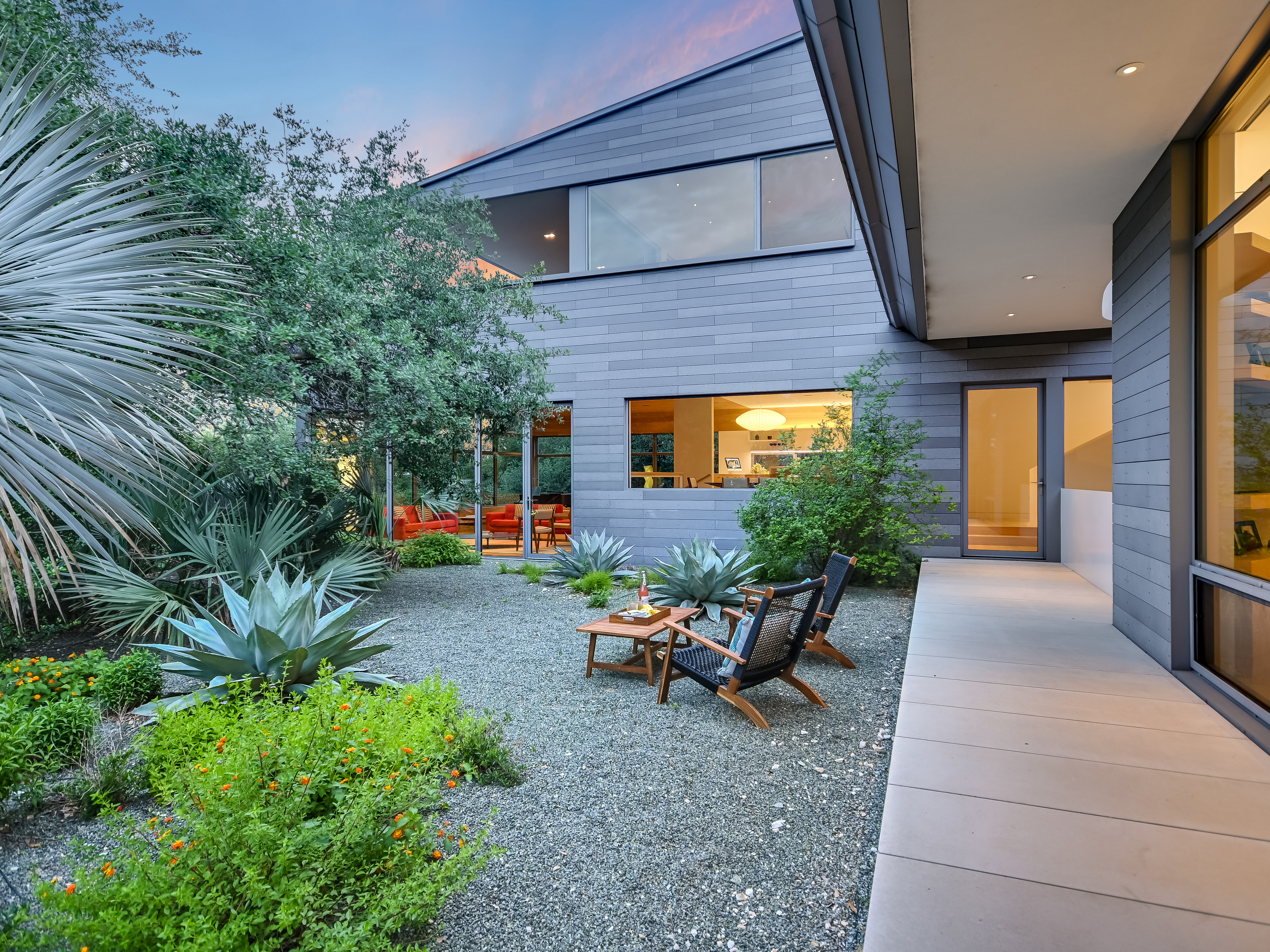 Zen courtyard with gravel, Adirondack seating, agave, and xeriscape plantings at dusk