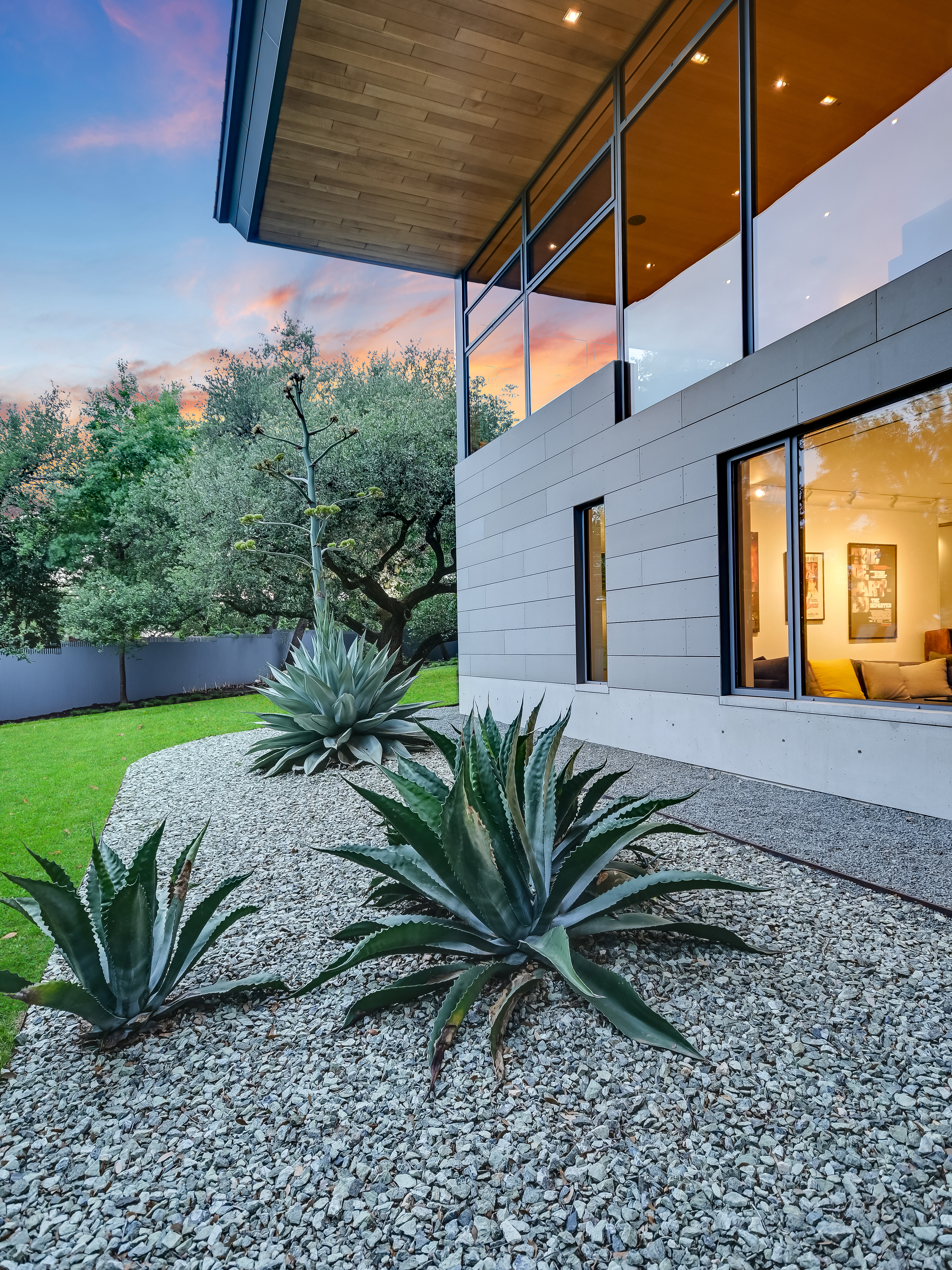 Rear glass walls reflecting courtyard garden at twilight