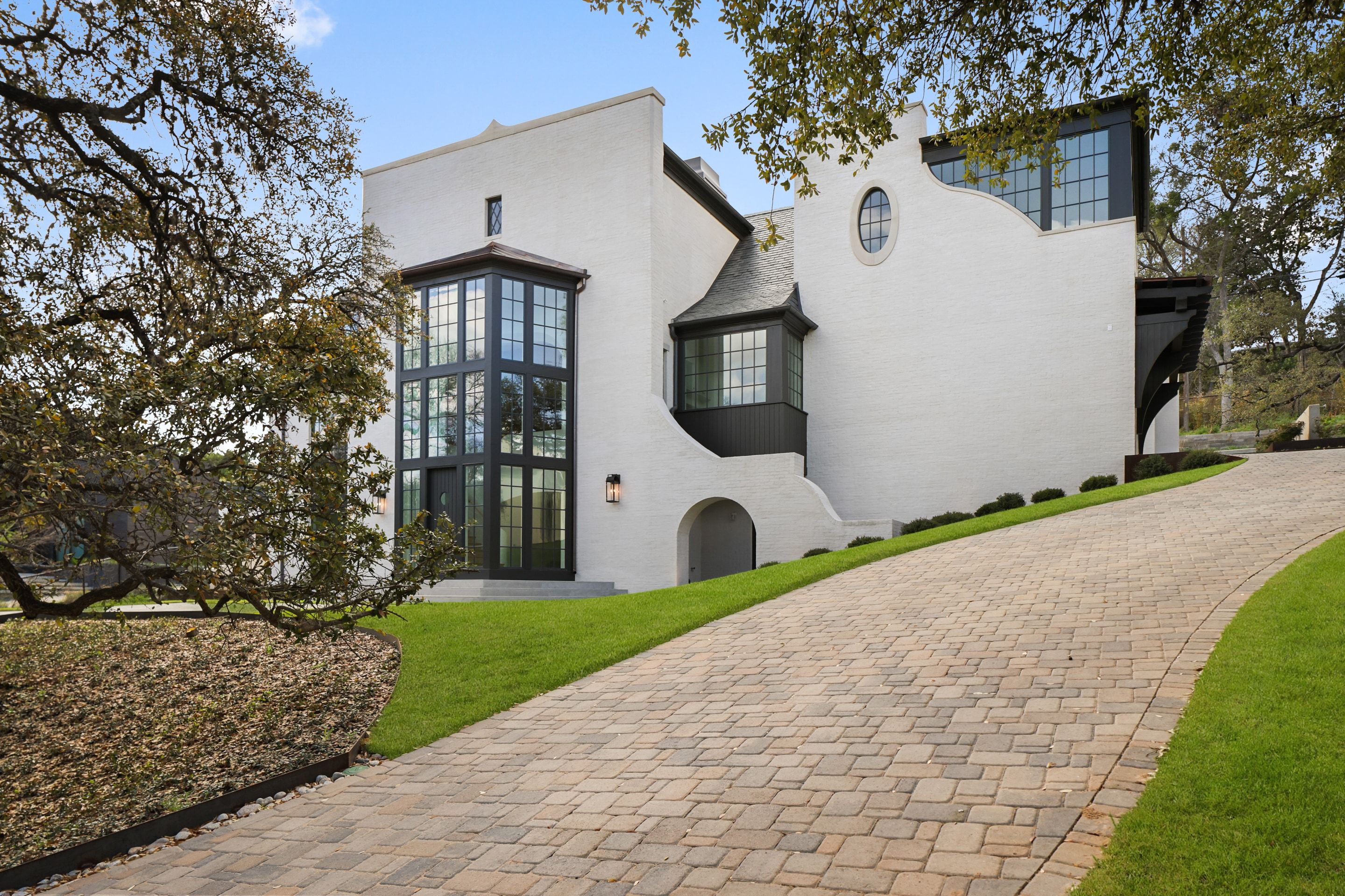 Brick-paved driveway approach with mature oaks