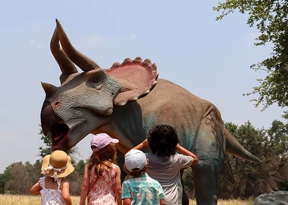 Visitors standing beside a large dinosaur model.