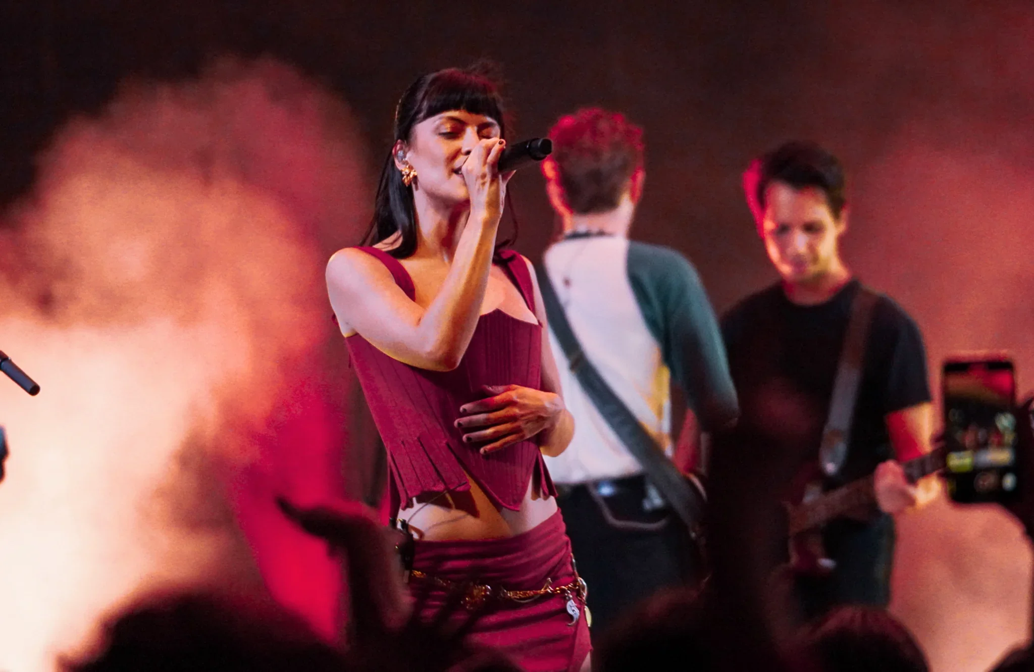 A singer and band under red stage lighting.
