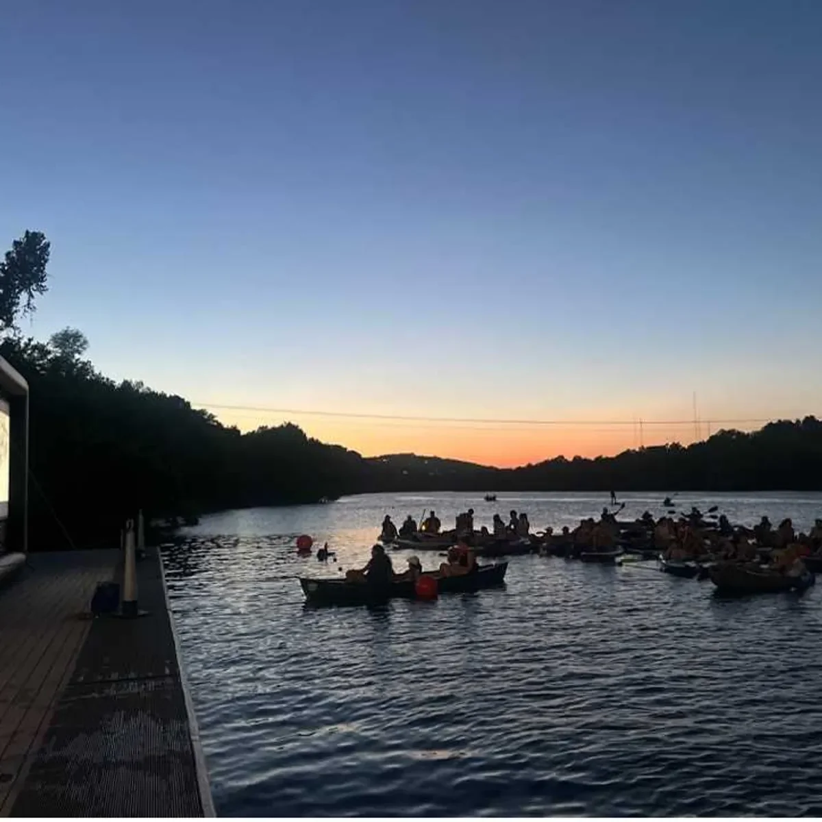 People paddling on a lake at sunset.