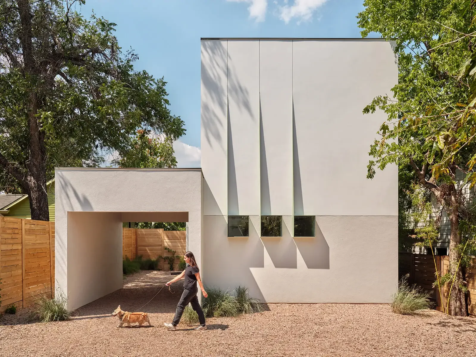 A contemporary home with pale walls and trees.