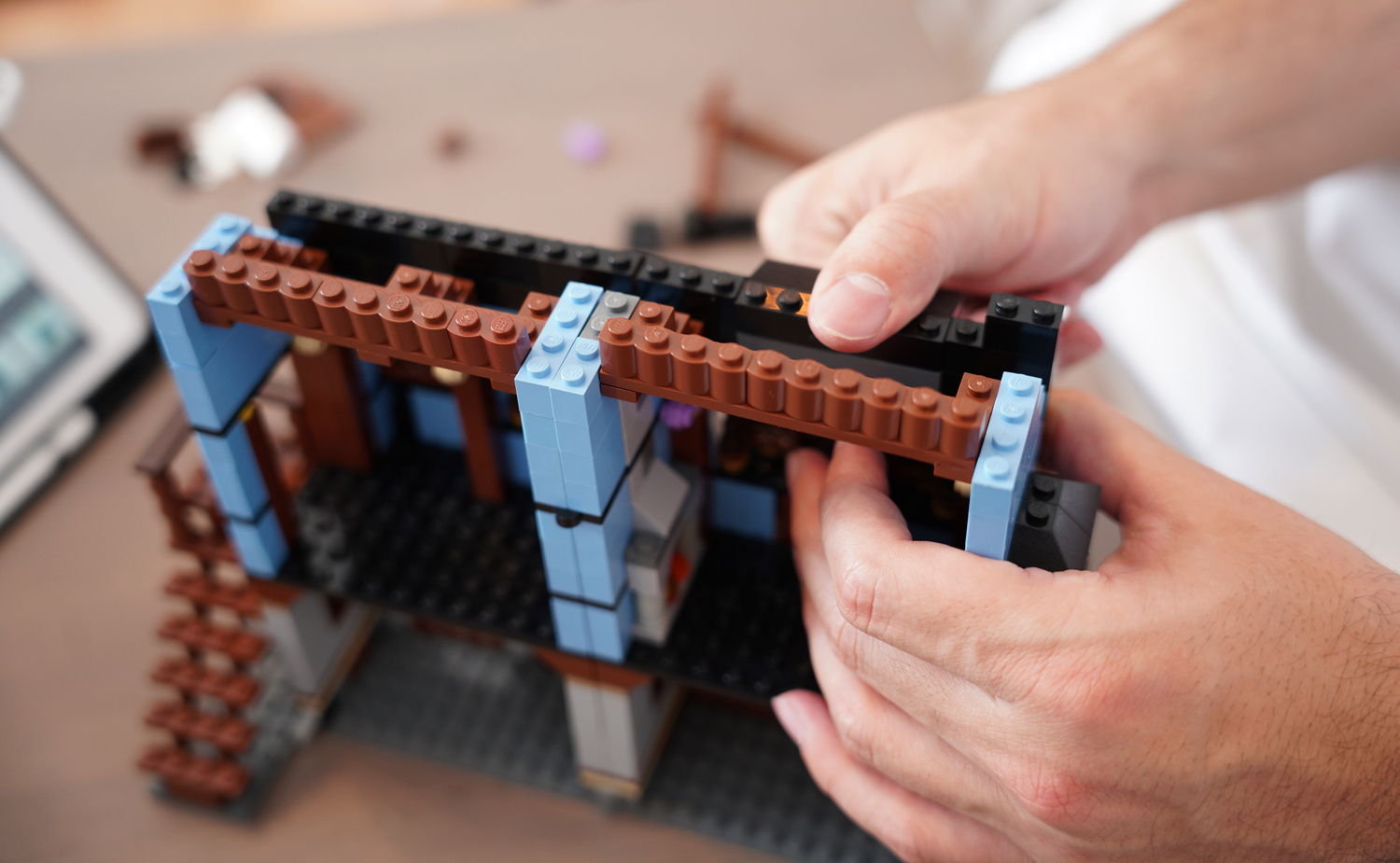 Hands assembling a LEGO structure.