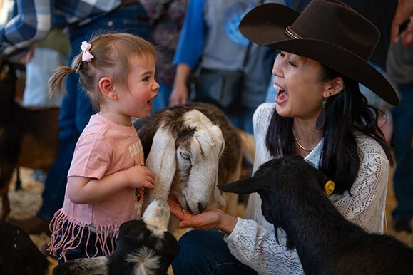 A child and an adult beside an animal.
