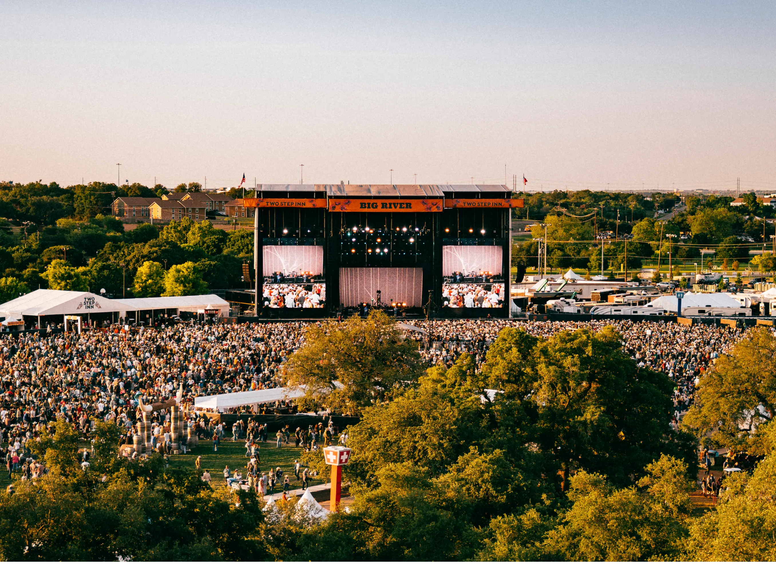A large crowd facing an outdoor concert stage.
