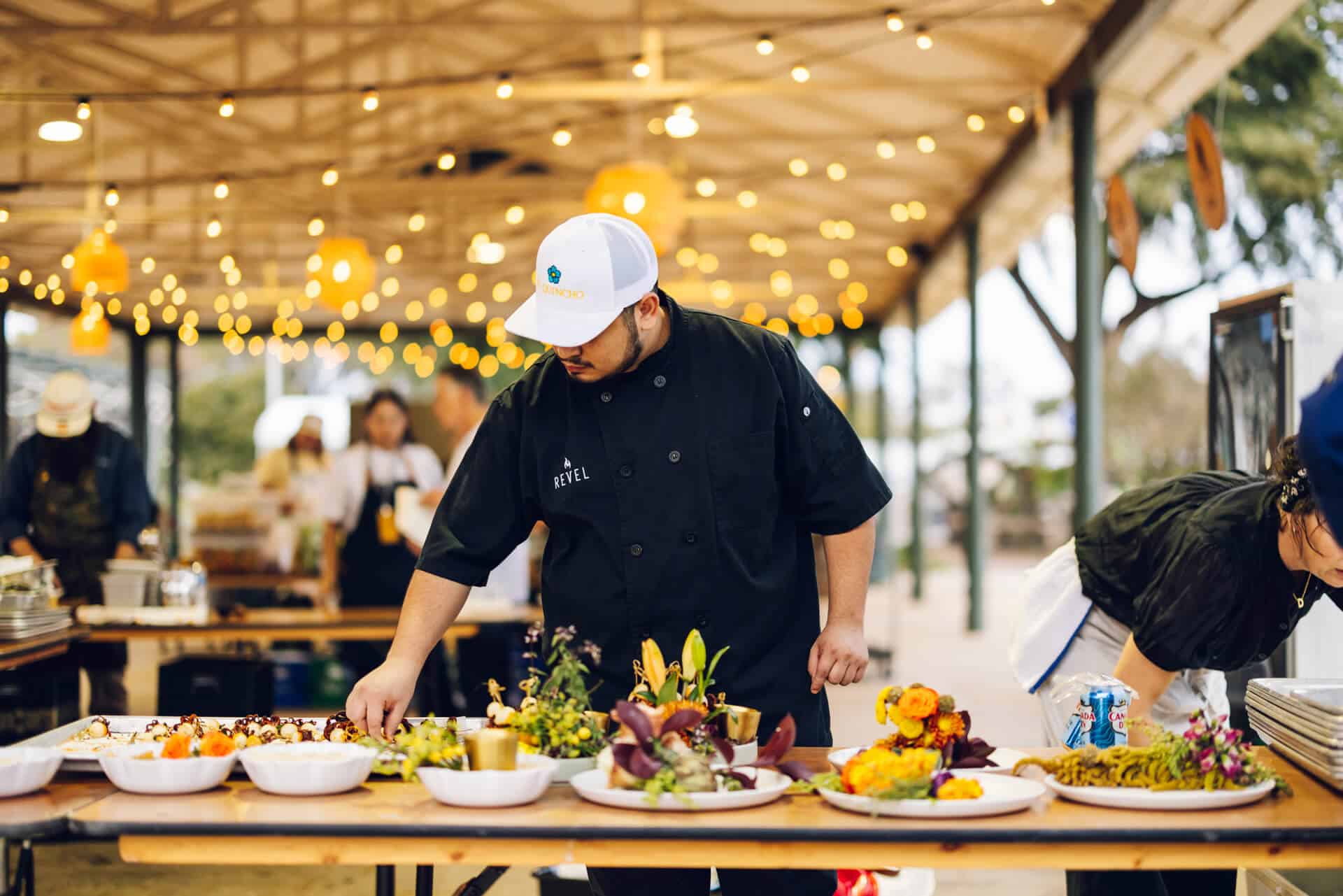 A cook preparing food at an outdoor dining event.