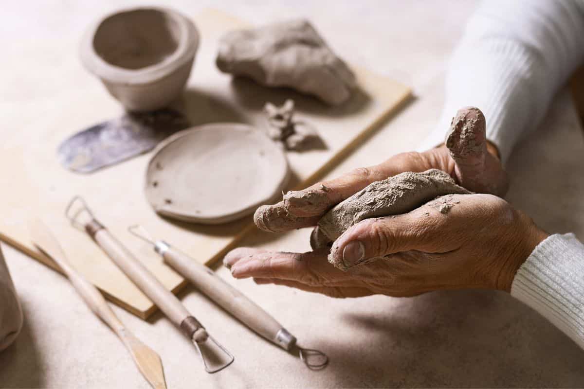 Hands shaping clay at a worktable.