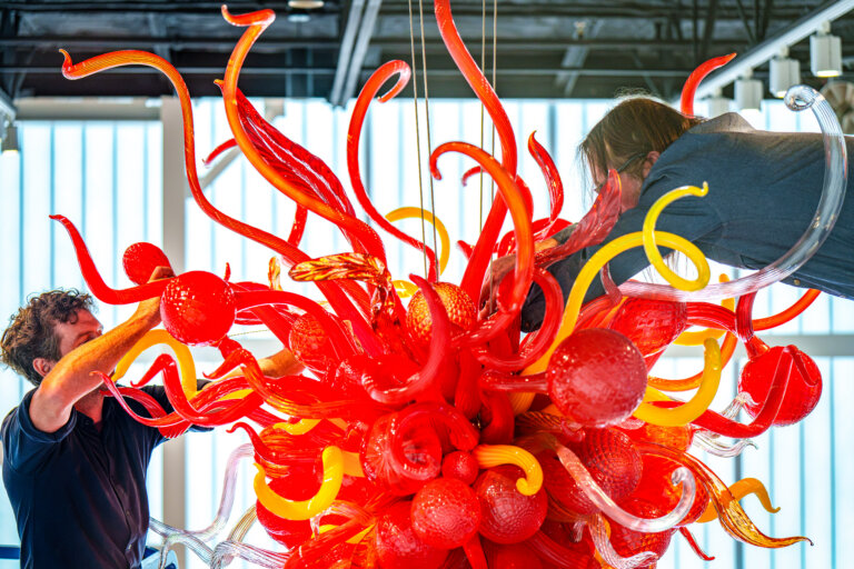 Glass artwork with workers nearby.