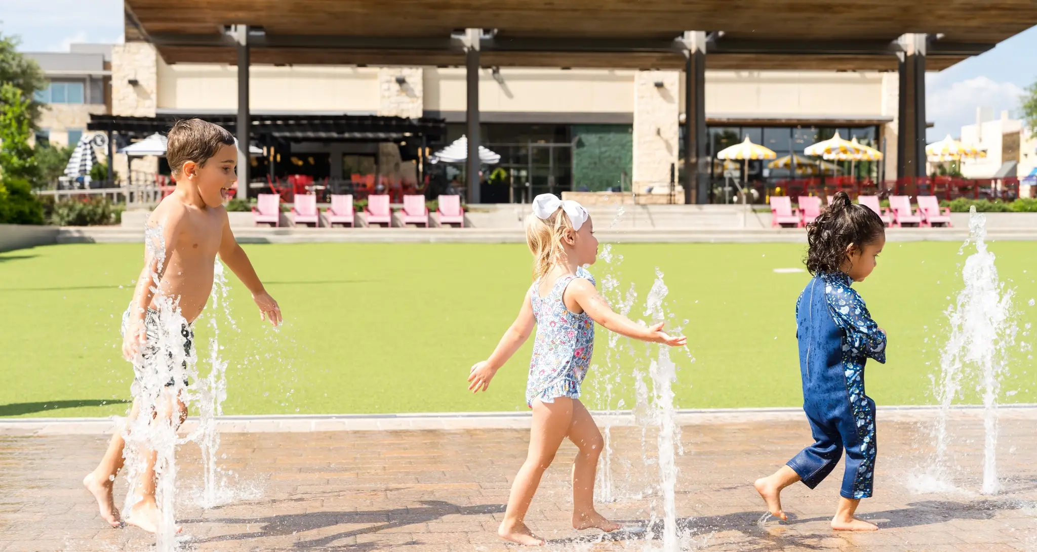 Children playing in ground-level water fountains.