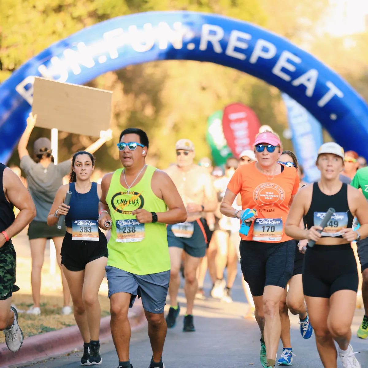 Runners beneath an arch at a relay event.