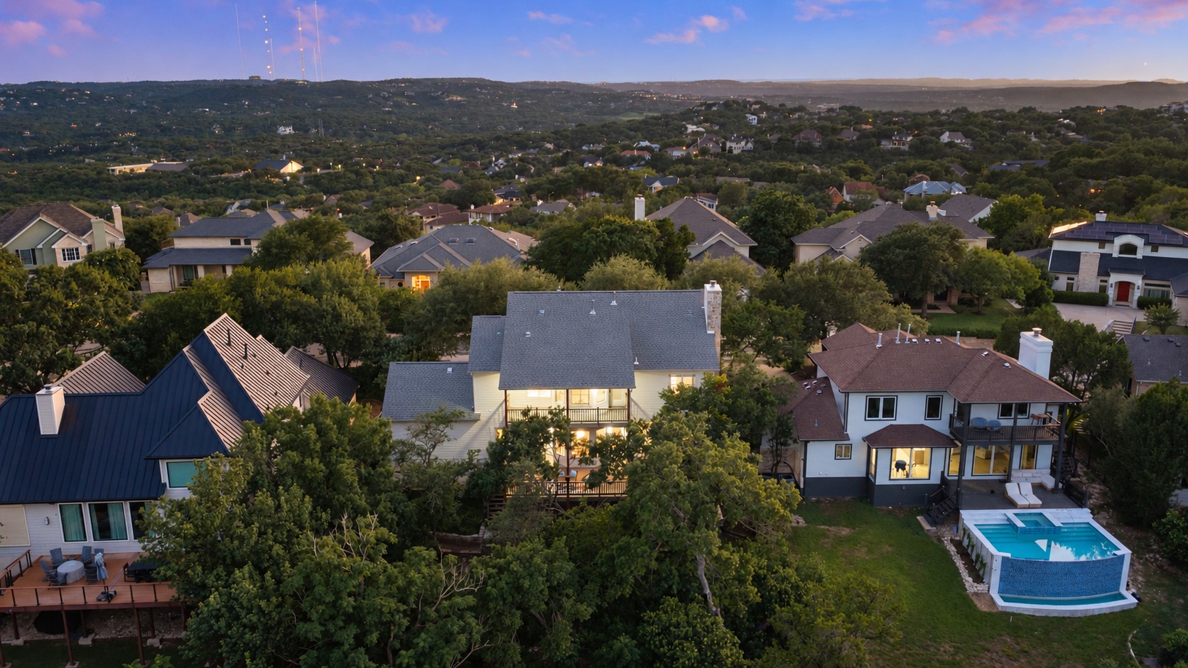 Aerial view of Edwards Mountain homes at dusk, with the Hill Country beyond.