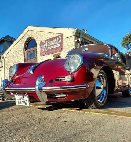 A red vintage Porsche parked in front of the Mozart's Coffee Roasters building.