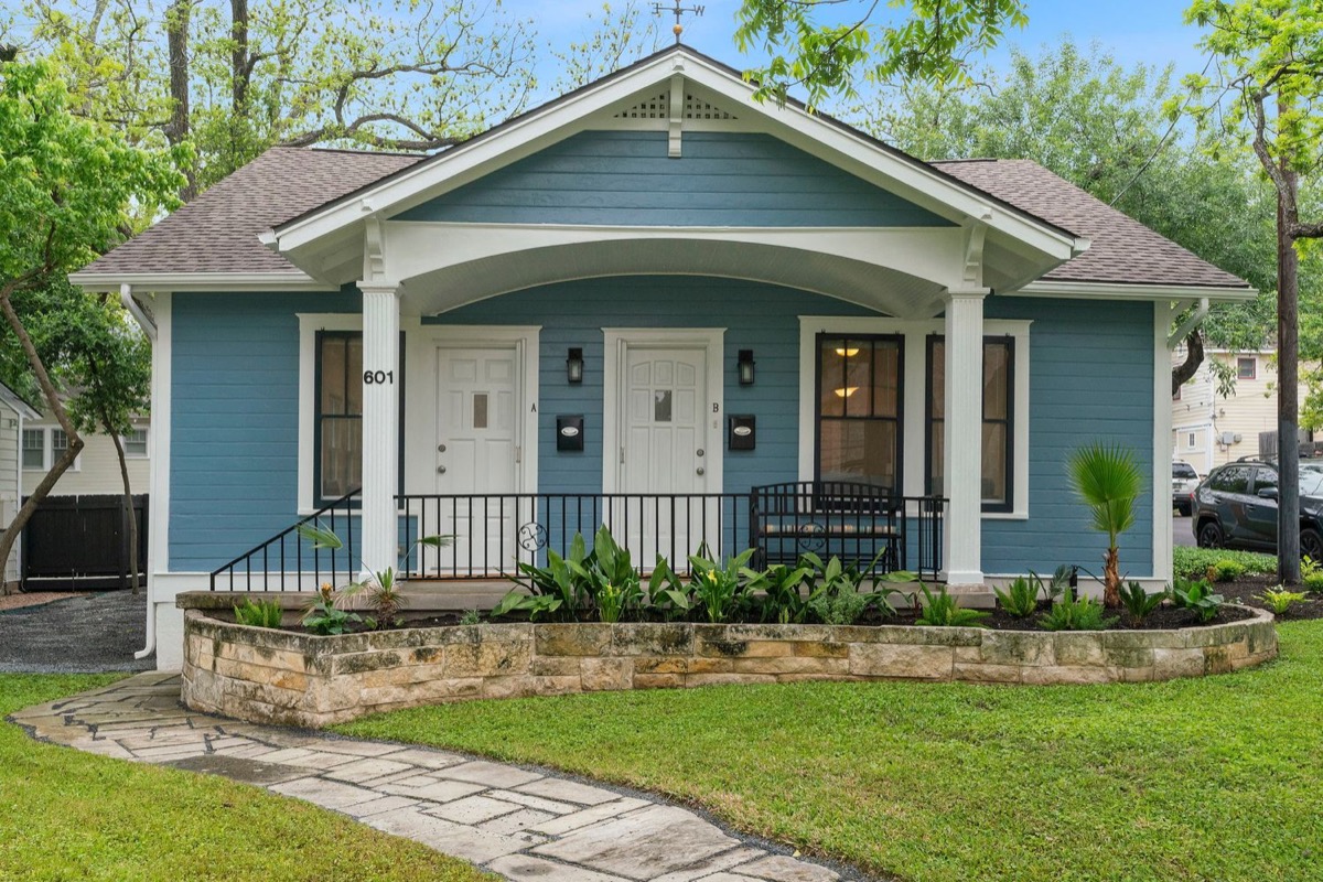 601 East 43rd Street, a blue duplex with two front doors, a covered porch and a stone-edged lawn.